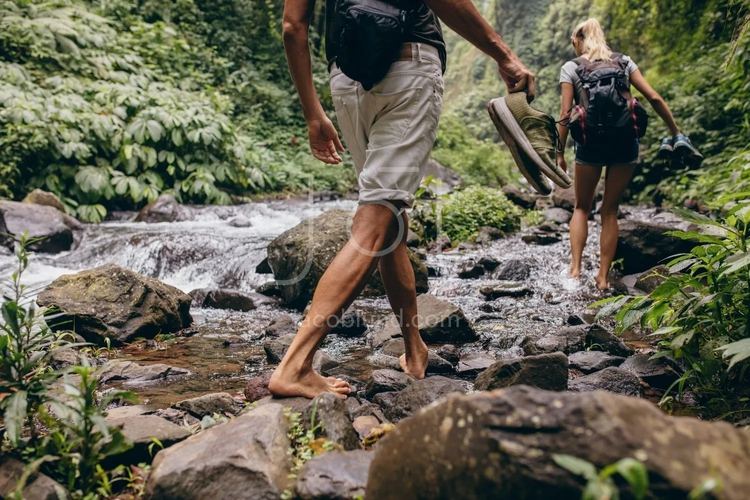 Couple crossing the stream barefooted